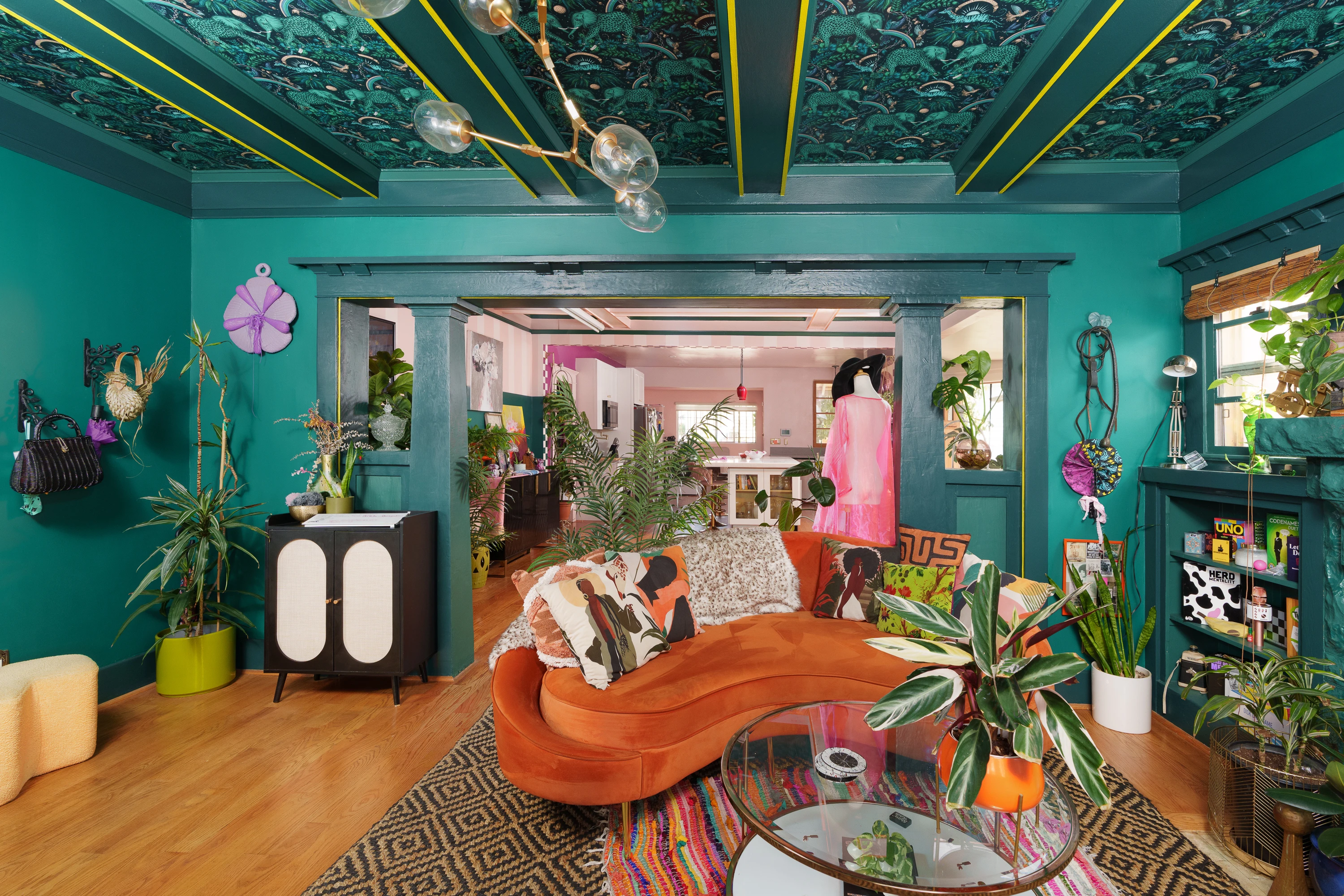 Teal living room with a hand-painted ceiling and curved velvet sofa